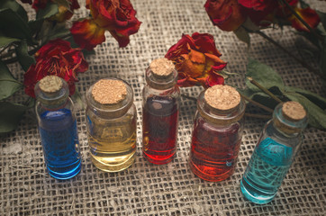 Herbal medicine concept. Bottles with color essential oils on sackcloth background.