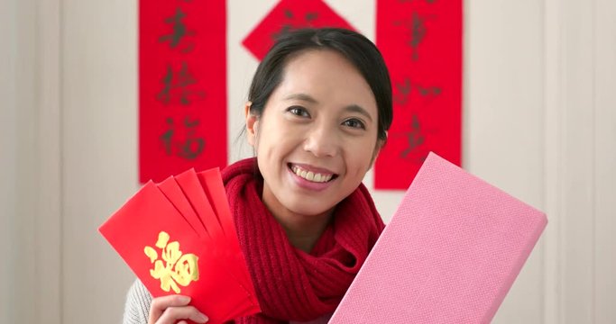 Woman holding red packet and gift box at home fro lunar new year
