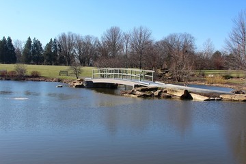 The walkway bridge across the pond in the park.