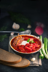 Traditional Ukrainian russian borscht. Plate of red beet root soup borsch on black rustic table. Beetroot soup. Traditional Ukrainian cuisine