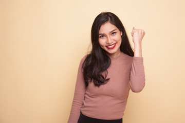 Successful  young Asian woman hold fist up.