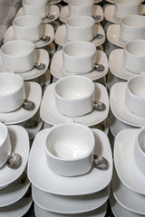 Smooth rows of white tea cups with spoons on a table in a restaurant