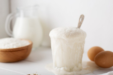 Rising yeast in the glass with spoon on white table.