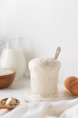 Fermented yeast rise in glass on white wooden table.