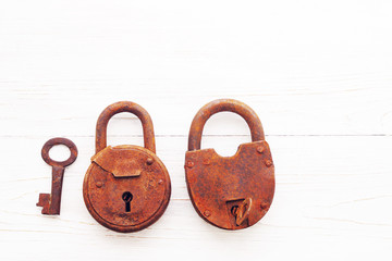 Two old rusty padlock on wooden white background, close up