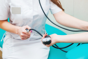 Close up view of female medicine doctor measuring blood pressure to her patient. Hands close up. Healthcare, healthy lifestyle and medical service concept