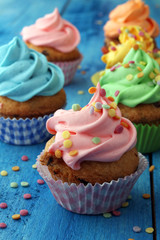 Tasty cupcakes on wooden background. Birthday cupcake in rainbow colors