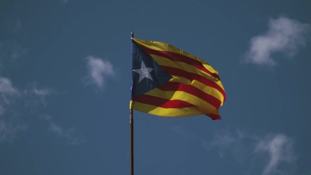 A flag of the Republic of Catalonia is waving because of a strong wind. The colors of the unofficial independence flag are red, yellow and blue, with a white star in the middle.