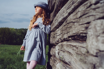 Teen girl in casual clothes and blue hat dreams leaning on a wooden wall. Active lifestyle. Youth fashion