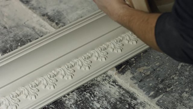 Worker removing silicone mold. Beautiful gypsum product. Stylish ornament on gypsum workpiece. Masterpiece of architecture workshop.