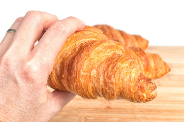 Hand holding a fresh French croissant isolated on white background