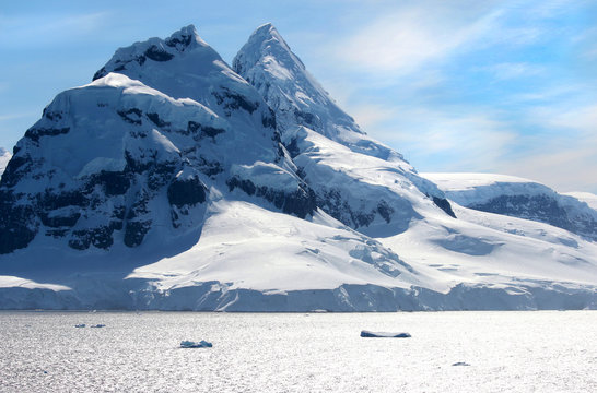 Antarctic ocean, Antarctica. Glacier Snow Covered Mountain. Dramatic blue Sky background 