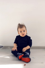 Naklejka premium baby sitting on the floor with red sole sneakers