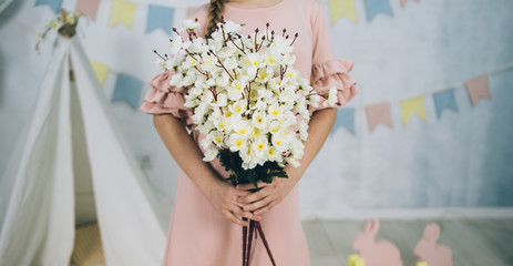 girl is holding flowers in her hands in dress in easter studio close