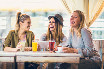 Group of female friends in cafe using digital tablet