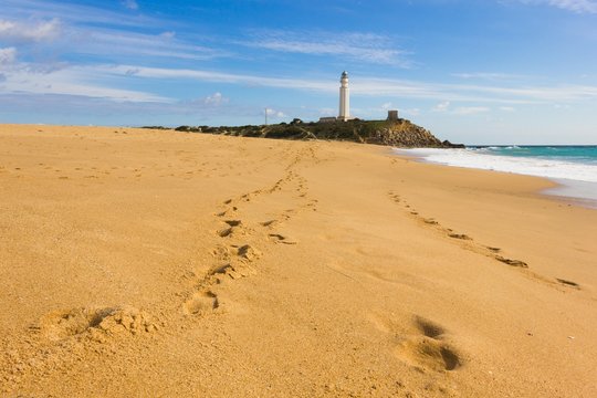 Footsteps on the sand at Zahora Beach leading to Trafalgar lighthouse in the province of Cadiz, Andalusia, south of Spain