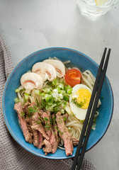 Asian ramen soup with beef, egg, chives and mushrooms in bowl. Top view
