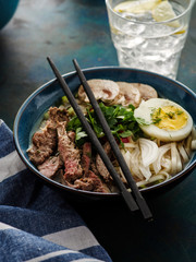 Asian ramen soup with beef, egg, chives and mushrooms in bowl.