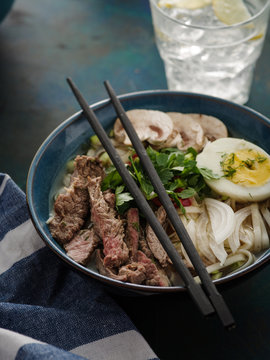 Asian ramen soup with beef, egg, chives and mushrooms in bowl.