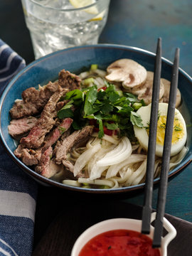 Asian ramen soup with beef, egg, chives and mushrooms in bowl.