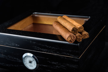 Cigars on a humidor against a black background