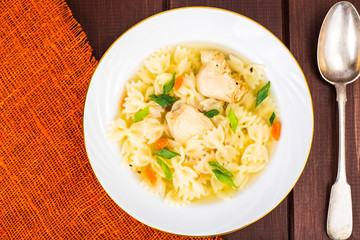 Chicken soup with farfalle in white plate