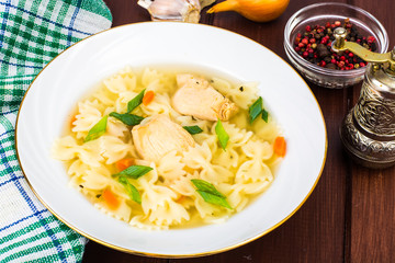 Chicken soup with farfalle in white plate
