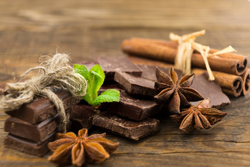 Fototapeta na wymiar Pieces of chocolate, cinnamon and star anise on a wooden table.