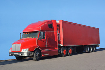 A big red truck stands on the asphalt.