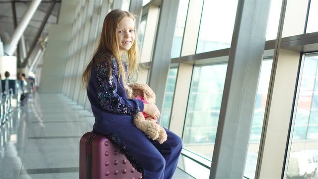 Adorable little girl with baggage in airport waiting for boarding