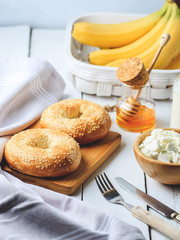 Bagel with cottage cheese , banana and honey. Concept of healthy breakfast. White wooden background.