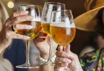 Three mature women drinking a toast with glass chalice of beer