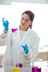 Fototapeta premium young woman scientist working with laboratory glassware with different colors liquid in a laboratory