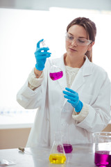 young woman scientist working with laboratory glassware with different colors liquid in a laboratory