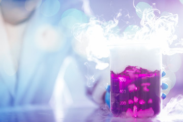hands of a scientist moving pink liquid with white smoke in laboratory glassware