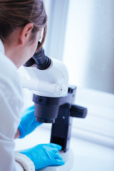 woman scientist looking through a microscope in laboratory