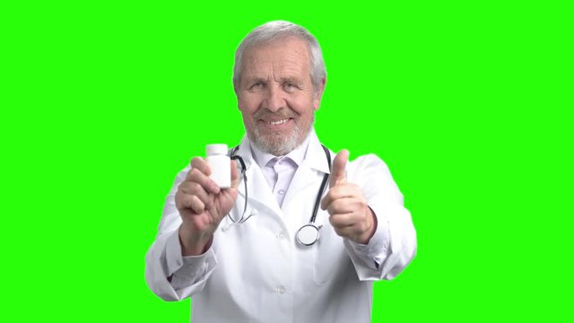 White bottle of pills and thumb up. Senior doctor recommed bottle of pills. Green screen hromakey background for keying.