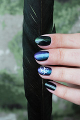 hand of a young girl with green manicure, which shows a sign of biological danger biohazard and...