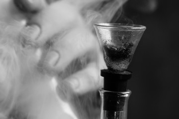 A man smokes bong cannabis weed. Smoke on a black background. Concepts of medical marijuana use and...