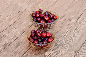 Berries of a sweet cherry in a glass bowl on a wooden background. Ripe red sweet cherry