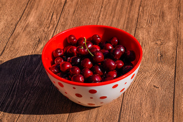 Berries of a sweet cherry on a wooden background in a plastic cup. Ripe red sweet cherry