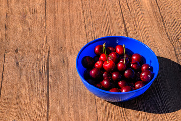 Berries of a sweet cherry on a wooden background in a plastic cup. Ripe red sweet cherry