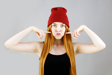 Funny pretty girl puffing out her cheeks against studio wall background. Headshot of charming red haired young woman making mouths while having fun indoors. People, lifestyle, youth and happiness