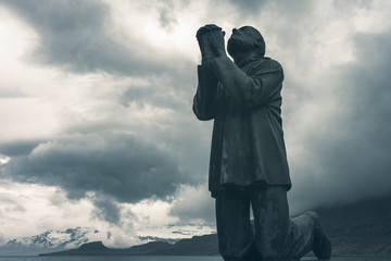 Dramatic clouds move over the Victims of the Sea monument in Eskifjordur, Sudur-Mulasysla, Iceland