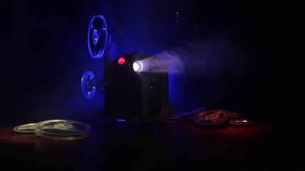Slider shot. Old style movie projector, still-life, close-up. Film projector on a wooden background with dramatic lighting and selective focus. Movies and entertainment concept