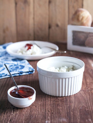 Proper nutrition and a healthy lifestyle. Cottage cheese on white plate on wooden background. Vertical. Selective focus.