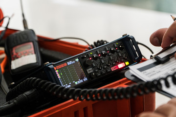 Fototapeta premium Multi-Track field recorder with equipment of filmmaking background. Sound engineer is recording sound and take a note of sound report.