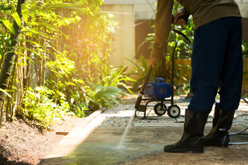 High pressure water cleaning,side view.Man cleaning dirty walkway with high pressure water jet ,professional cleaning services..