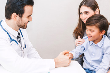 Doctor holding hand little boy with care on doctors table in hospital.healthcare and medicine