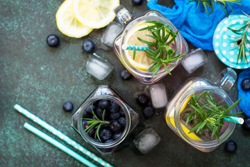 Mason jar mugs with homemade refreshing drink with blueberries and rosemary. The concept of proper nutrition and health or detoxification. Copy space, top view of a flat background.